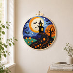 Whimsical haunted village and halloween pumpkins needle felt wall art displayed in a bright home interior