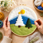 Creating the white and green christmas trees on grass wool painting by hand with a felting needle