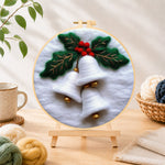 Finished white christmas bells with holly needle felting displayed on a wooden easel