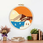 Finished white house by blue sea under orange sky artwork displayed on a wall