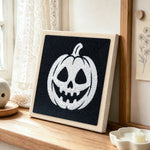 White jack‑o‑lantern punch needle artwork displayed on a table