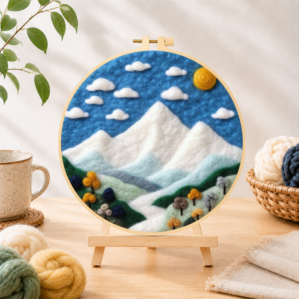 Finished white mountain peaks under the blue sky needle felting displayed on a wooden easel