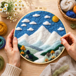 Creating the white mountain peaks under the blue sky wool painting by hand with a felting needle