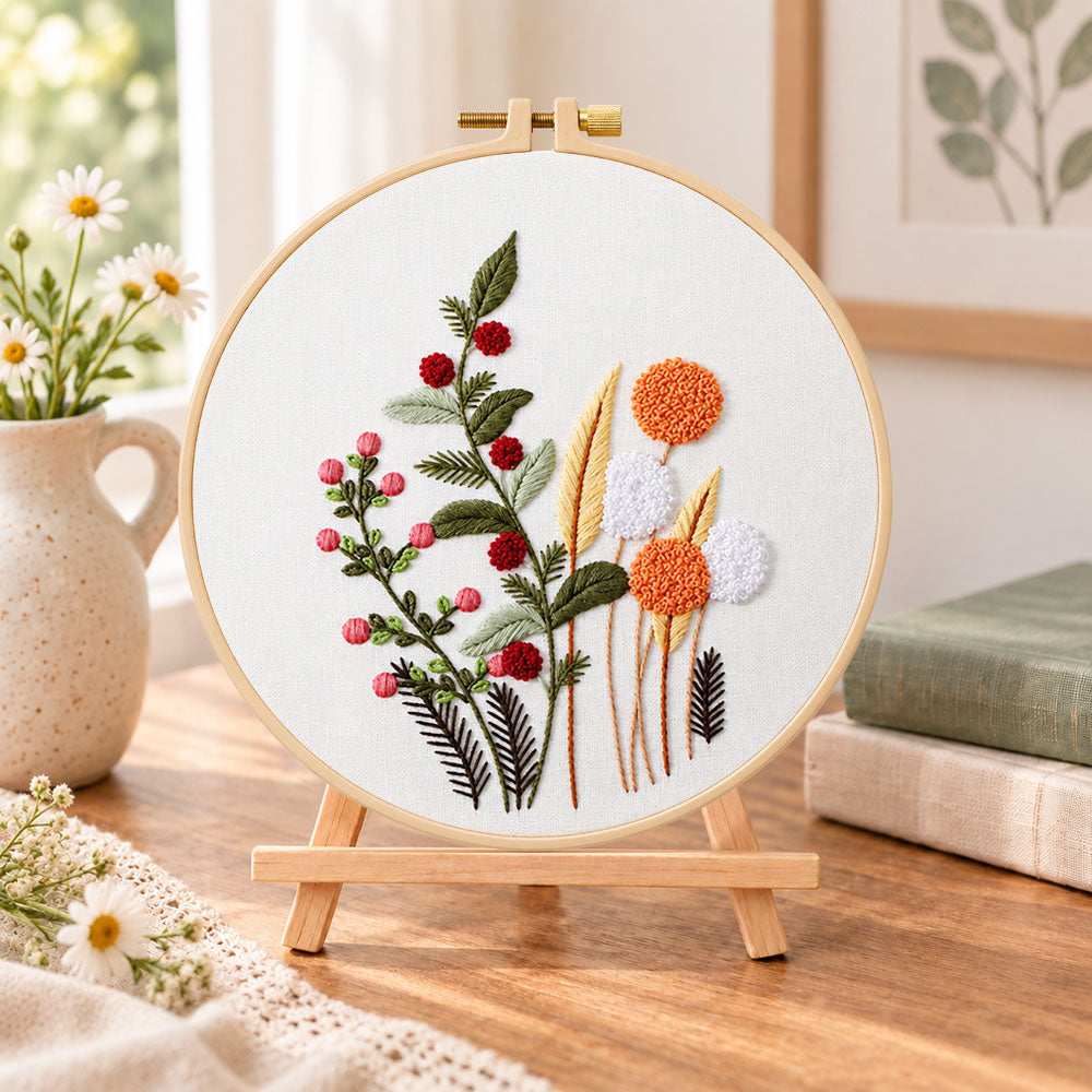 Wild berry and dandelion blooms embroidery kit finished hoop displayed on a wooden stand as cozy tabletop decor
