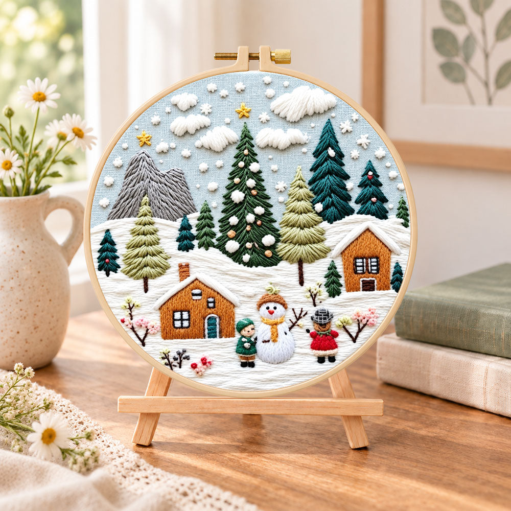 Winter snowy village embroidery kit finished hoop displayed on a wooden stand as cozy tabletop decor