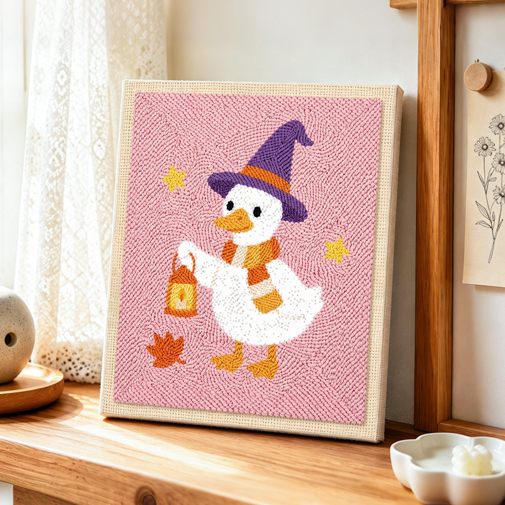 Witch duck holding lantern punch needle artwork displayed on a table