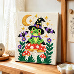 Witch frog on mushroom punch needle artwork displayed on a table
