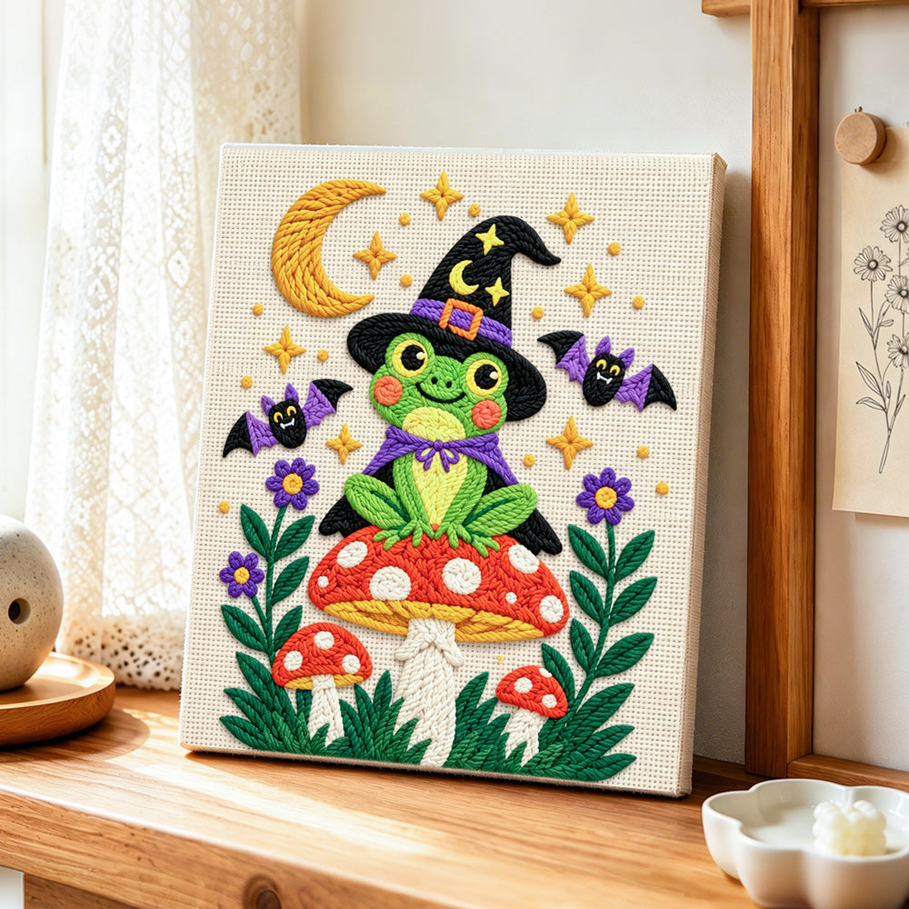 Witch frog on mushroom punch needle artwork displayed on a table