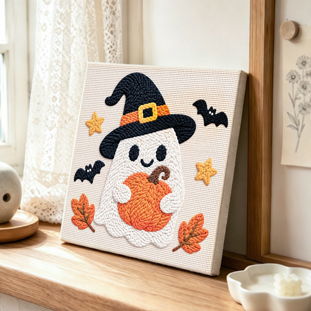 Witch ghost holding pumpkin punch needle artwork displayed on a table