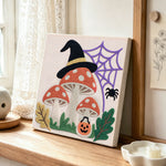 Witch hat mushrooms with spider web punch needle artwork displayed on a table