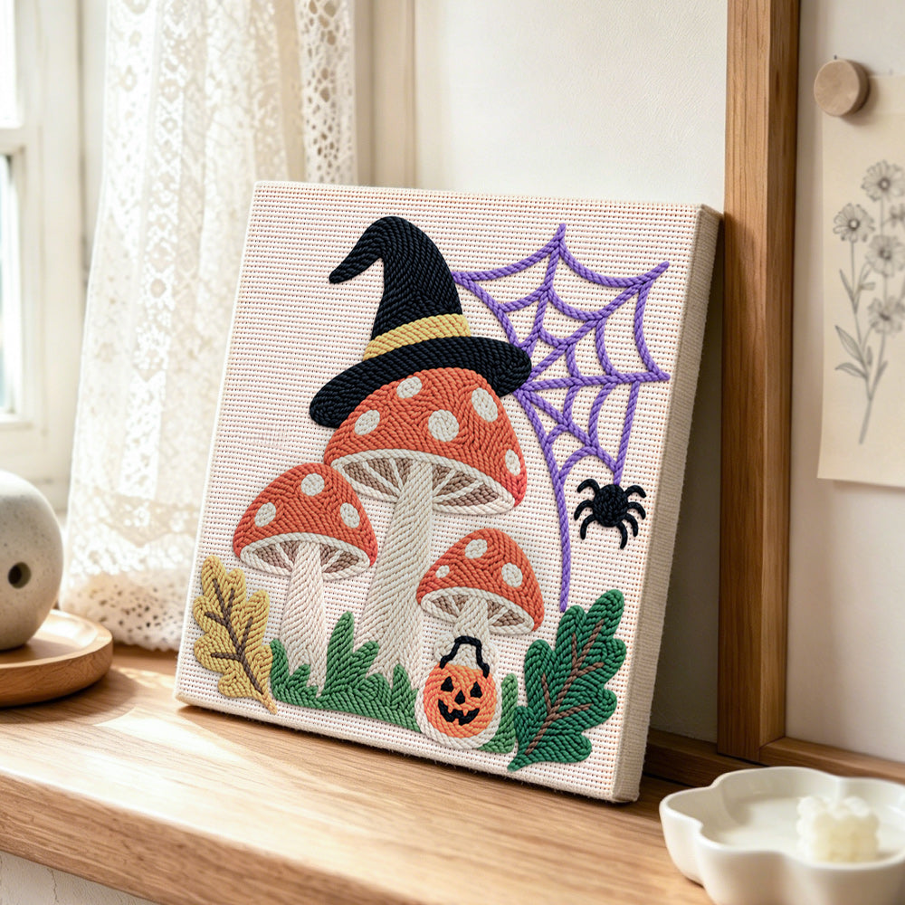Witch hat mushrooms with spider web punch needle artwork displayed on a table