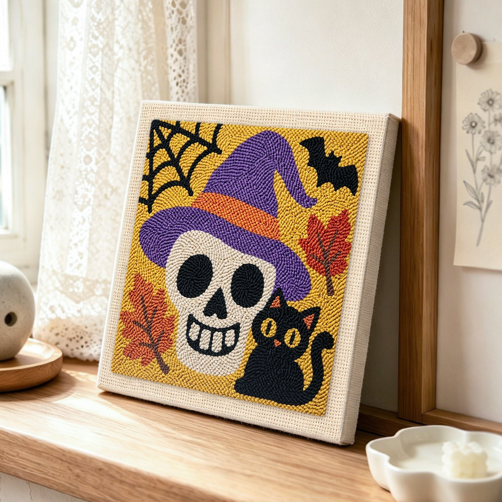 Witch hat skull and black cat punch needle artwork displayed on a table