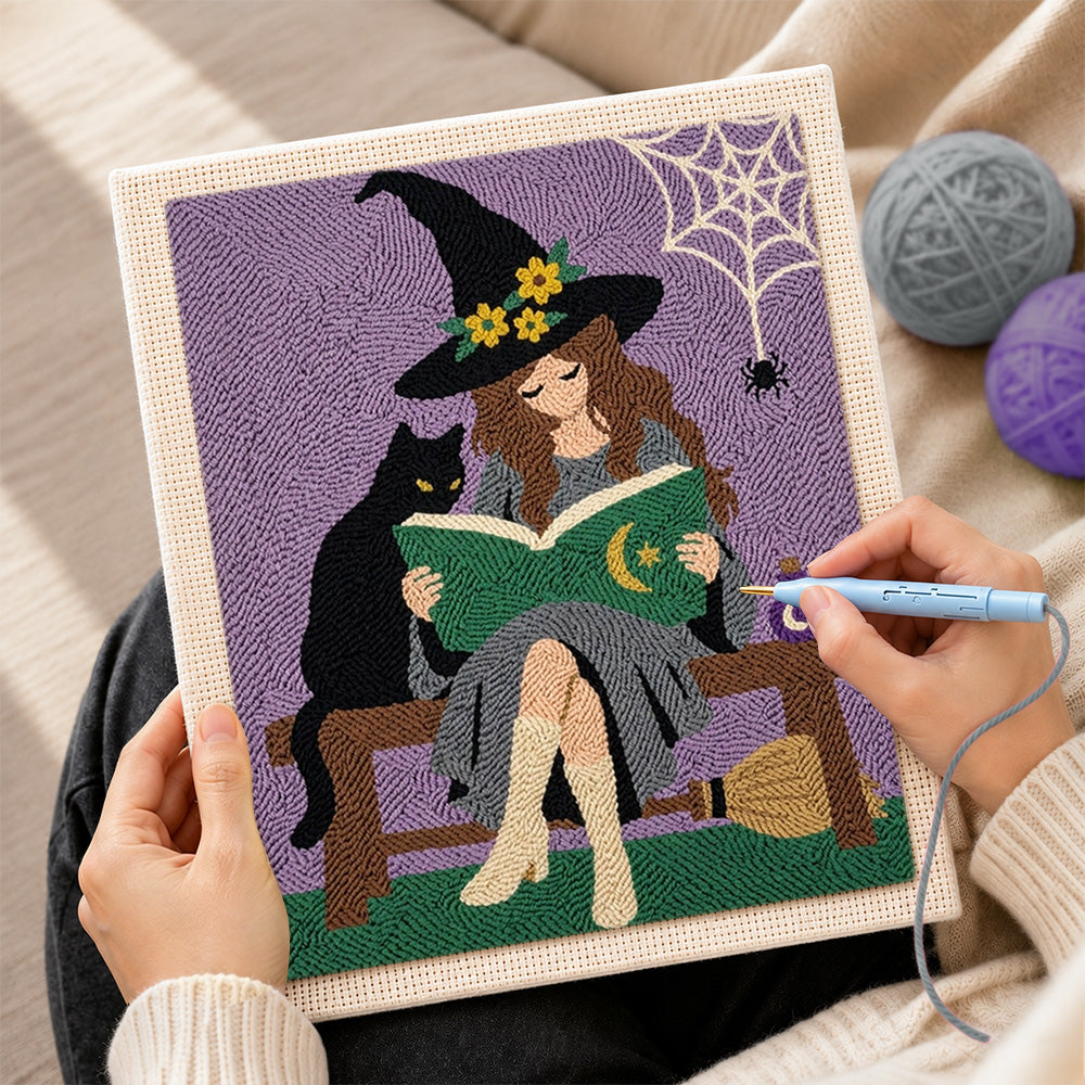 Creating handmade witch reading beside black cat punch needle artwork