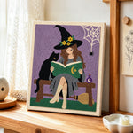 Witch reading beside black cat punch needle artwork displayed on a table
