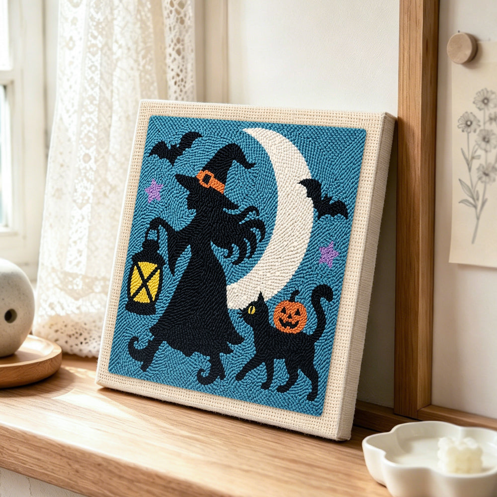 Witch silhouette under moon punch needle artwork displayed on a table