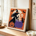 Witch stirring magic cauldron punch needle artwork displayed on a table