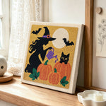 Witch watering pumpkins punch needle artwork displayed on a table