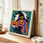Witch with pumpkin heads punch needle artwork displayed on a table