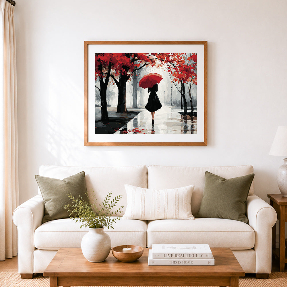 Finished woman with red umbrella in rainy forest cross stitch artwork displayed as home decor