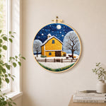 Yellow barn and white trees under the winter moon needle felt wall art displayed in a bright home interior