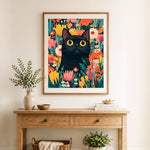 Finished yellow-eyed black cat among summer flowers cross stitch artwork displayed as home decor